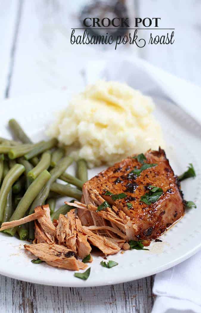 A slice of pork roast, green beans and mashed potatoes on a white plate.