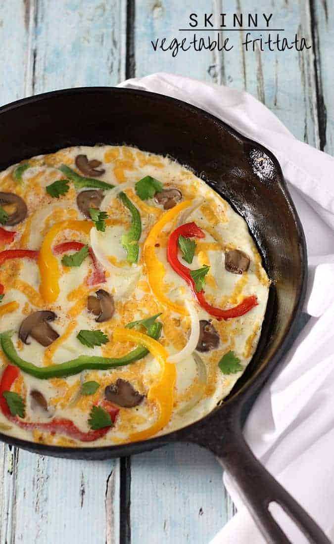 Overhead view of a vegetable frittata in a cast iron skillet on a blue wooden surface.