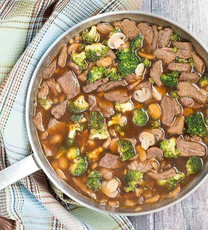 Overhead view of a skillet with beef, broccoli and mushrooms in sauce in a skillet.