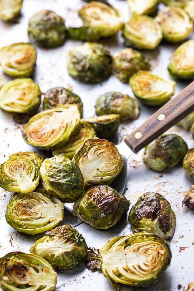 Oven roasted brussels sprouts on a baking sheet with a spatula