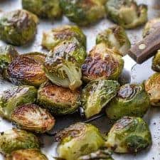 Roasted brussels sprouts on a baking sheet with a spatula