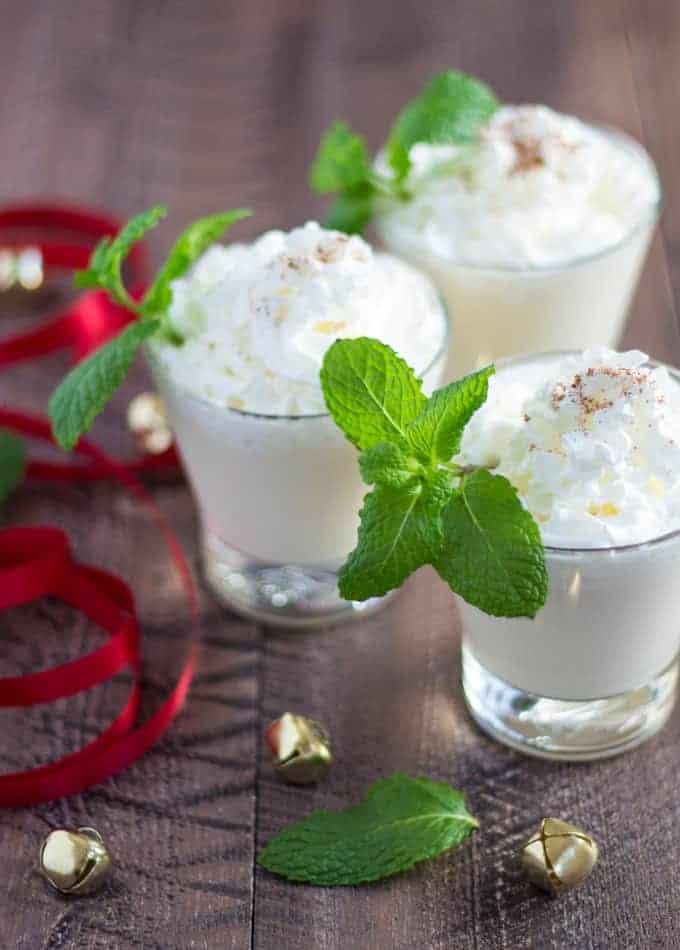 Three cocktails topped with whipped cream and garnished with fresh mint sprigs.