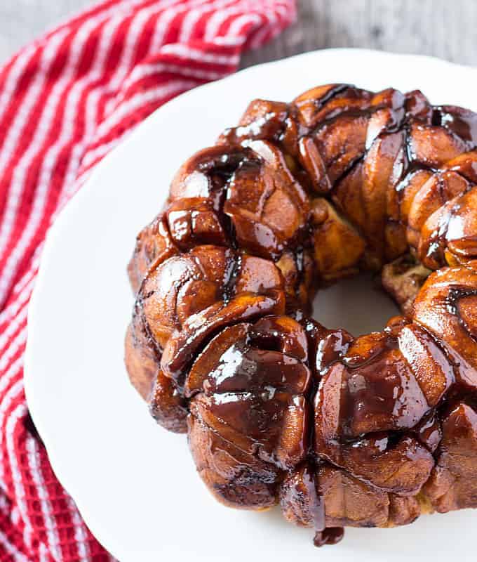 Overhead view of cinnamon roll monkey bread on a white plate by a red striped towel.