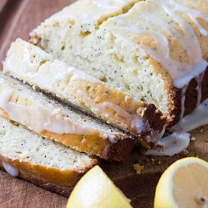 Closeup view of a loaf of sliced glazed lemon bread with poppy seeds.