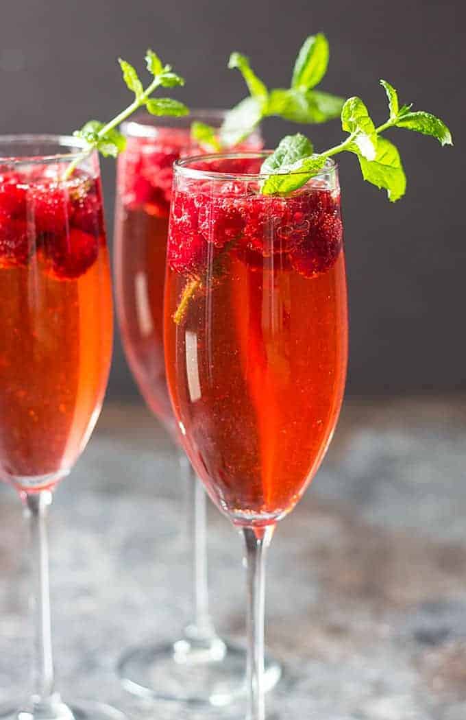 Champagne punch in three flutes garnished with fresh mint sprigs.