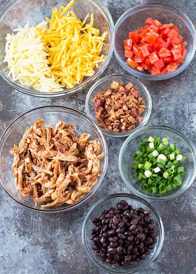 Overhead view of bowls of ingredients for barbecue chicken nachos.
