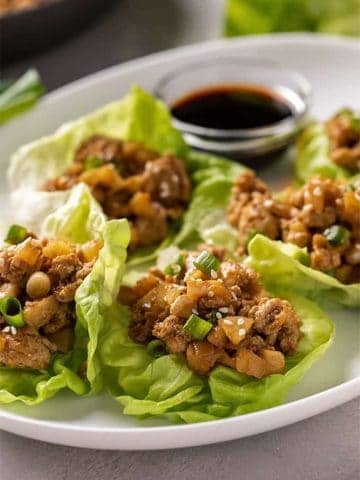 Lettuce wraps with ground chicken on an oval white plate
