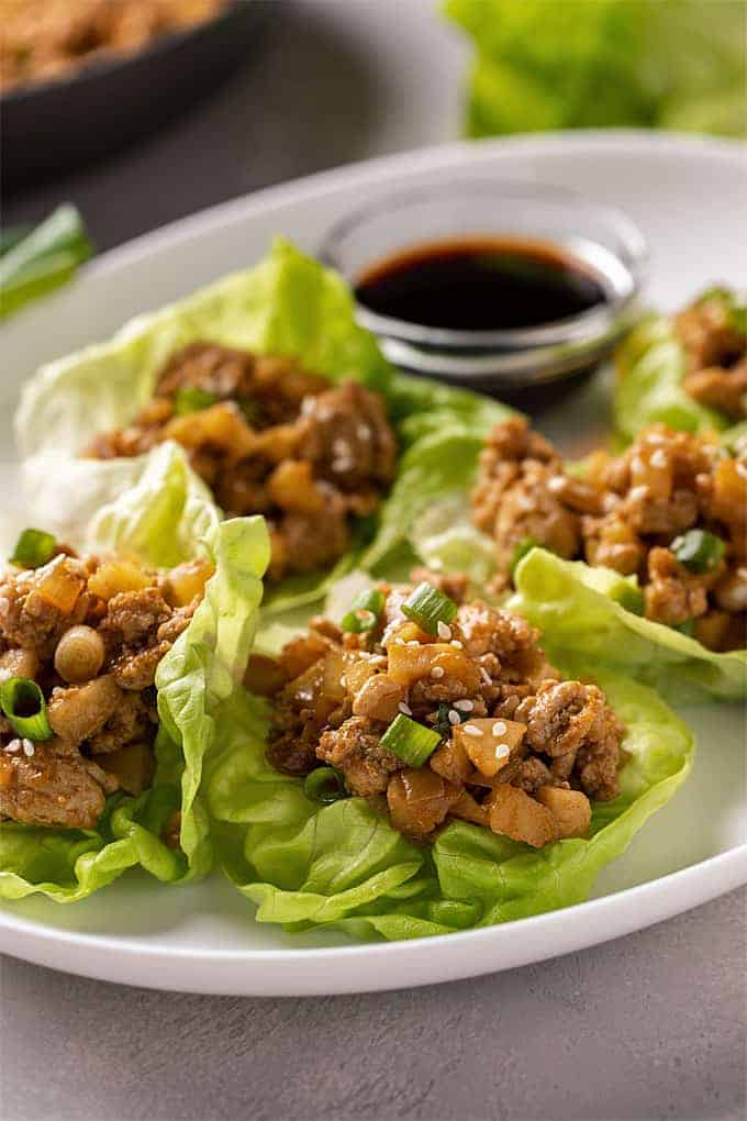 Lettuce wraps with ground chicken on an oval white plate.