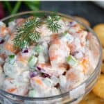 A closeup of shrimp salad garnished with dill with overlay text.