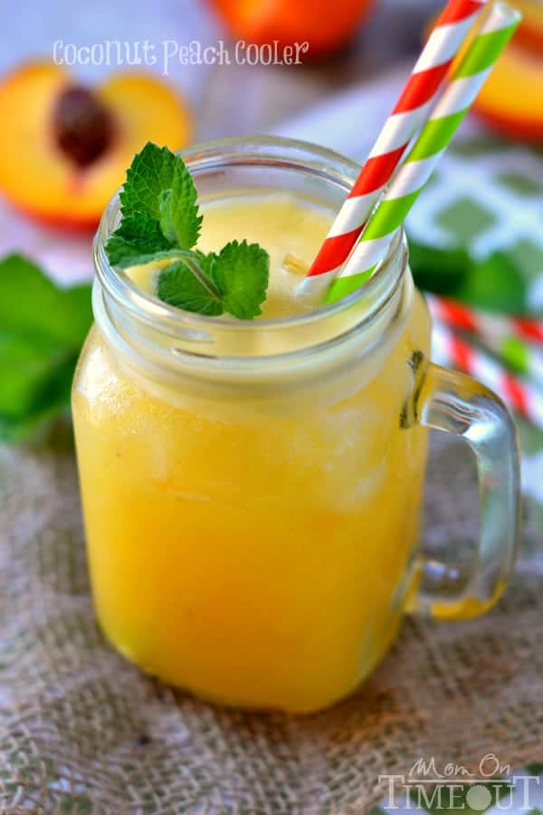 A coconut peach frozen drink in a glass jar garnished with fresh mint.