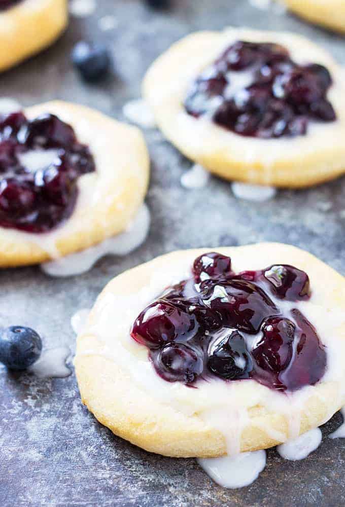 Closeup view of canned biscuit danish topped with blueberry pie filling and glaze.