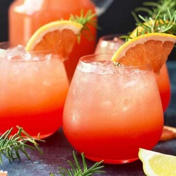 Front view of three cocktails garnished with grapefruit and fresh rosemary.