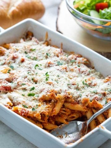 Chicken Parmesan Casserole in a white baking dish with a serving spoon