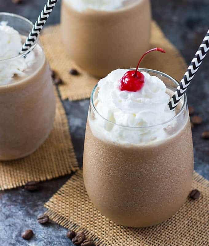 Frozen coffee cocktail in three glasses with black and white paper straws.