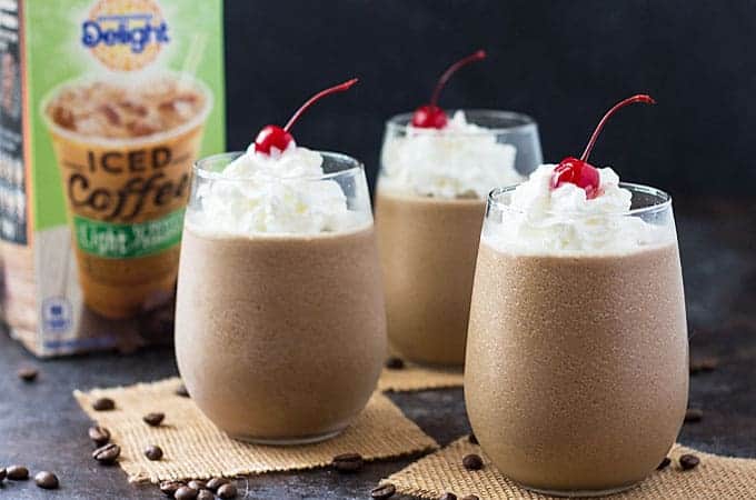 Frozen coffee cocktail in three glasses with a carton of iced coffee in the background.