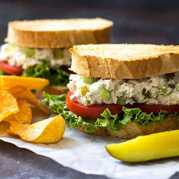 Closeup view of two wahoo fish salad sandwiches on a piece of parchment paper.