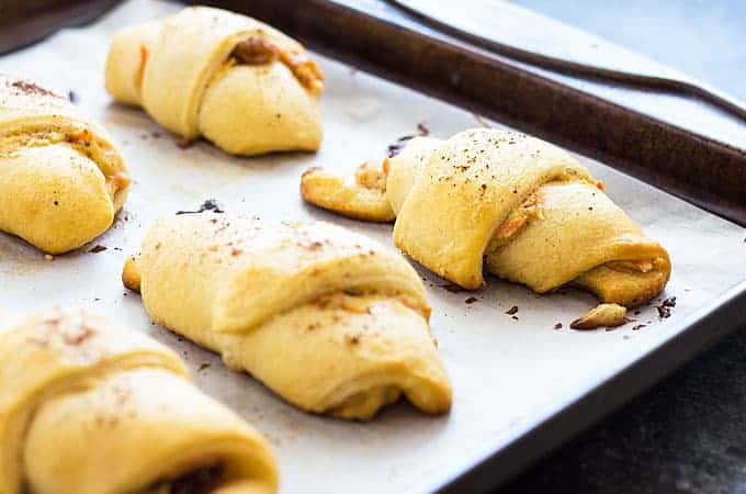 Baked carrot crescent rolls on a baking sheet lined with parchment paper.