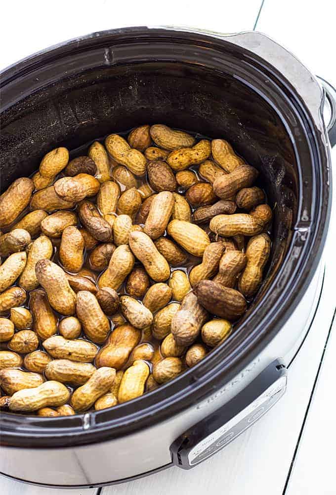 Overhead view of boiled peanuts in an oval crock pot.