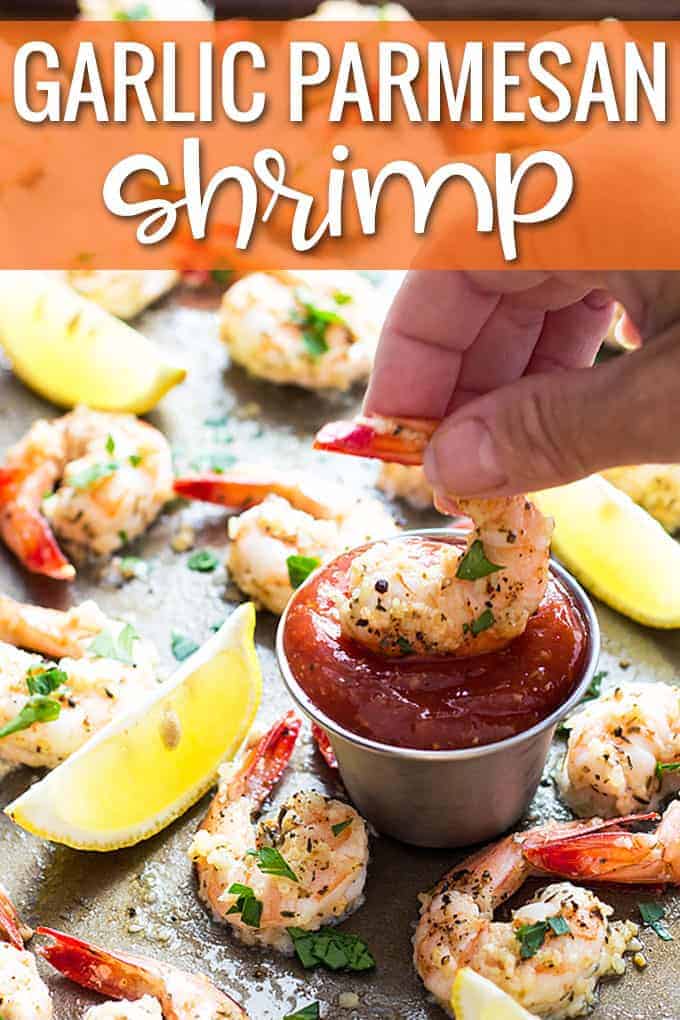 A hand dipping a shrimp into a stainless condiment cup of cocktail sauce.