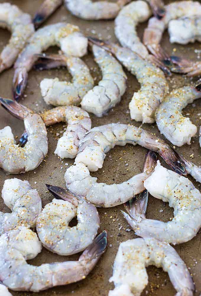 Overhead closeup view of seasoned raw peeled shrimp with tails left on.