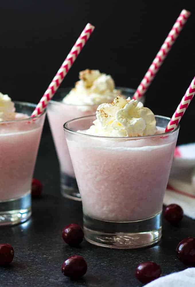 Front view of three cranberry pina coladas topped with whipped topping.