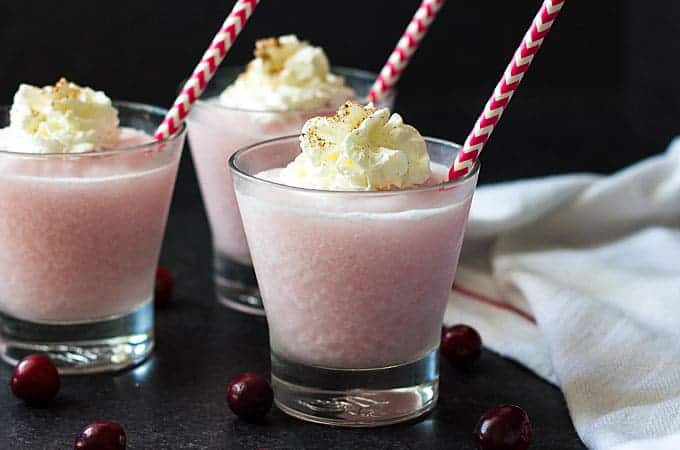 Front view of three pink cranberry coladas topped with whipped cream.