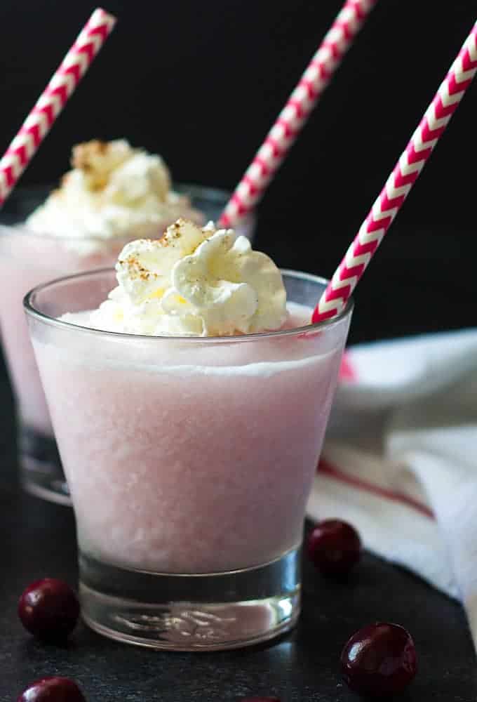 Front closeup view of a frozen cranberry pina colada topped with whipped topping.