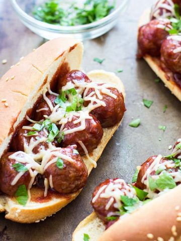 A closeup of a meatball sub topped with shredded mozzarella and parsley.