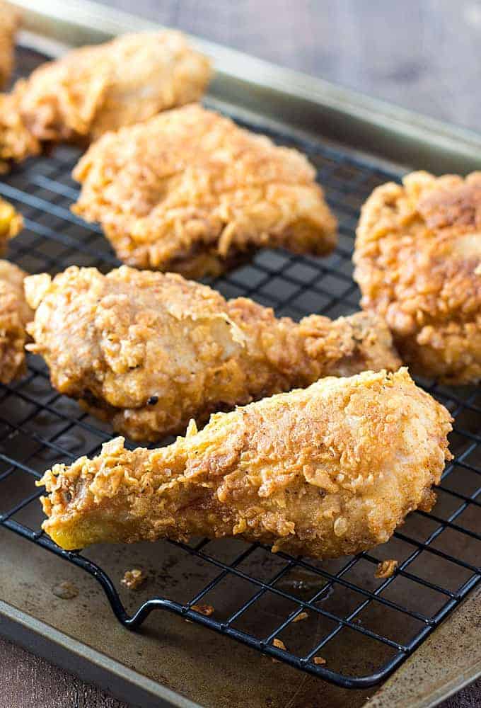 Fried chicken on a black wire rack placed in a rimmed baking sheet.