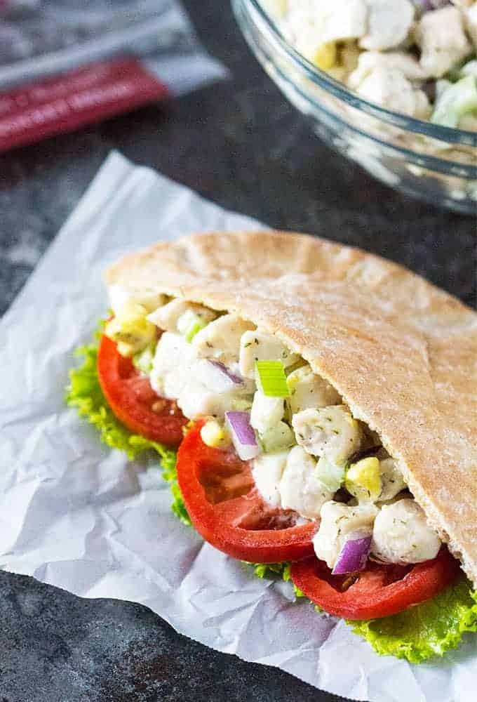 A closeup view of a pita pocket filled with chicken salad, lettuce and tomato.