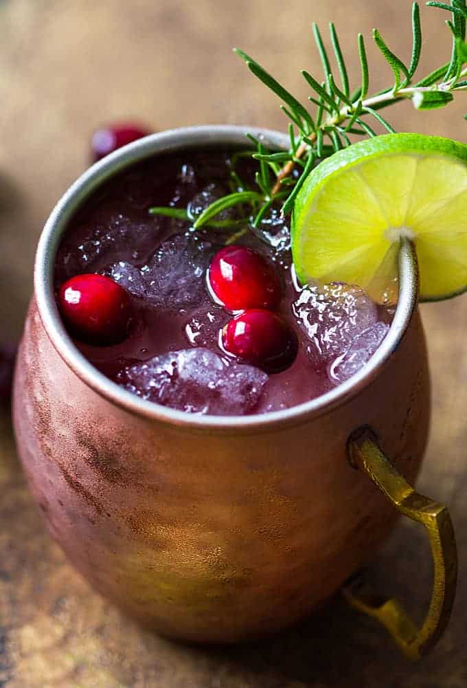 Closeup view of a cranberry moscow mule drink in a copper mug.
