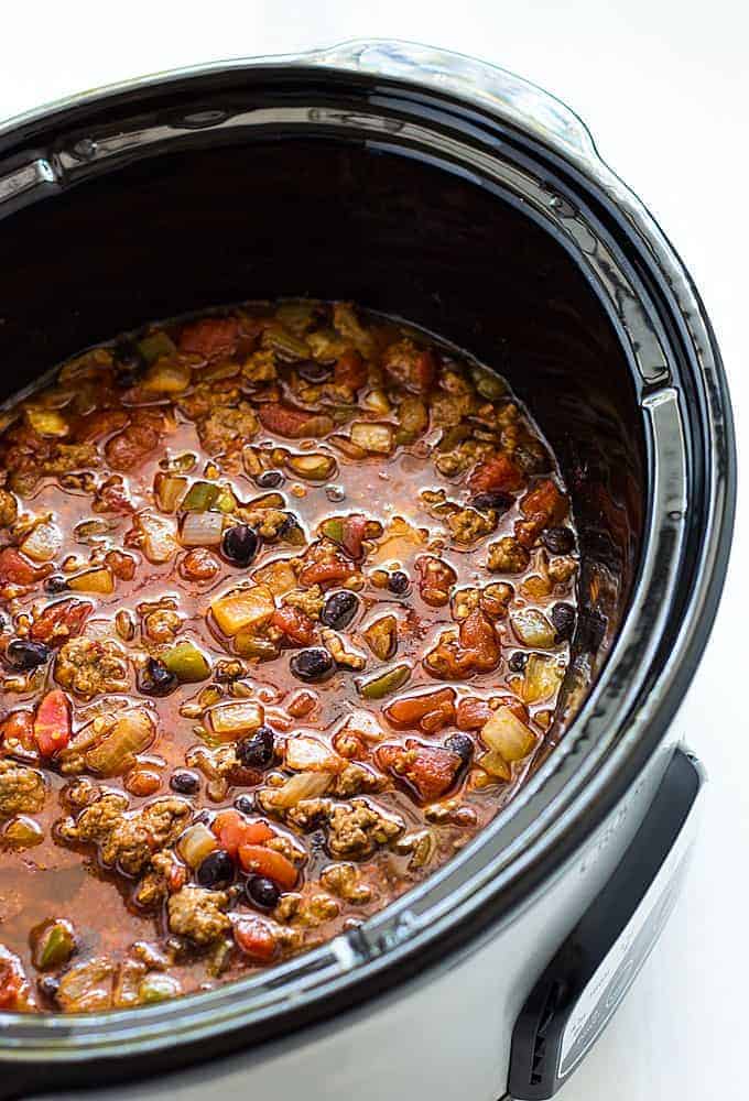 Chili with beef and black beans in an oval slow cooker.