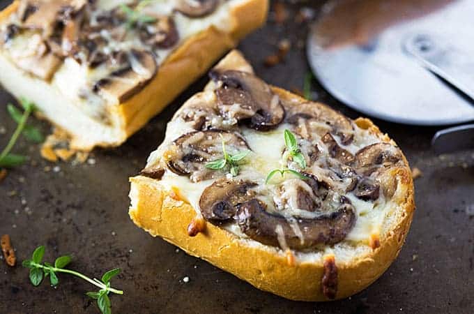 Front closeup view of a slice of white mushroom french bread pizza.