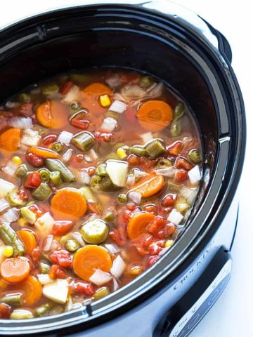 Closeup view of vegetable soup in an oval slow cooker.