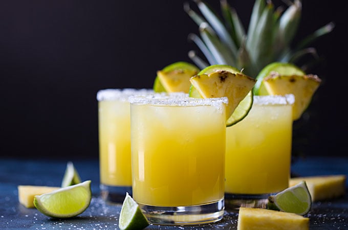 Front view of three glasses of garnished pineapple margarita cocktails.
