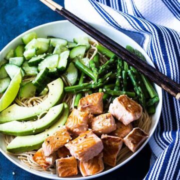 Overhead view of salmon noodle bowl with vegetables in a white bowl