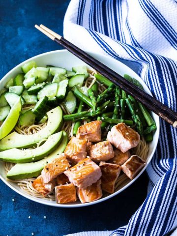 Overhead view of salmon noodle bowl with vegetables in a white bowl