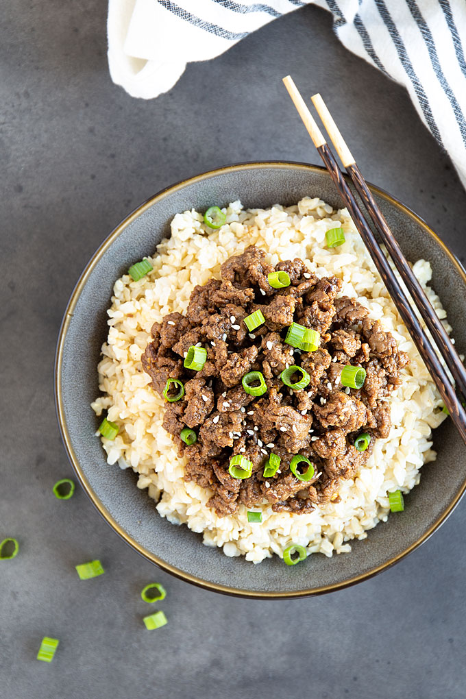 Overhead view of Korean ground beef over rice in a bowl with chopsticks.