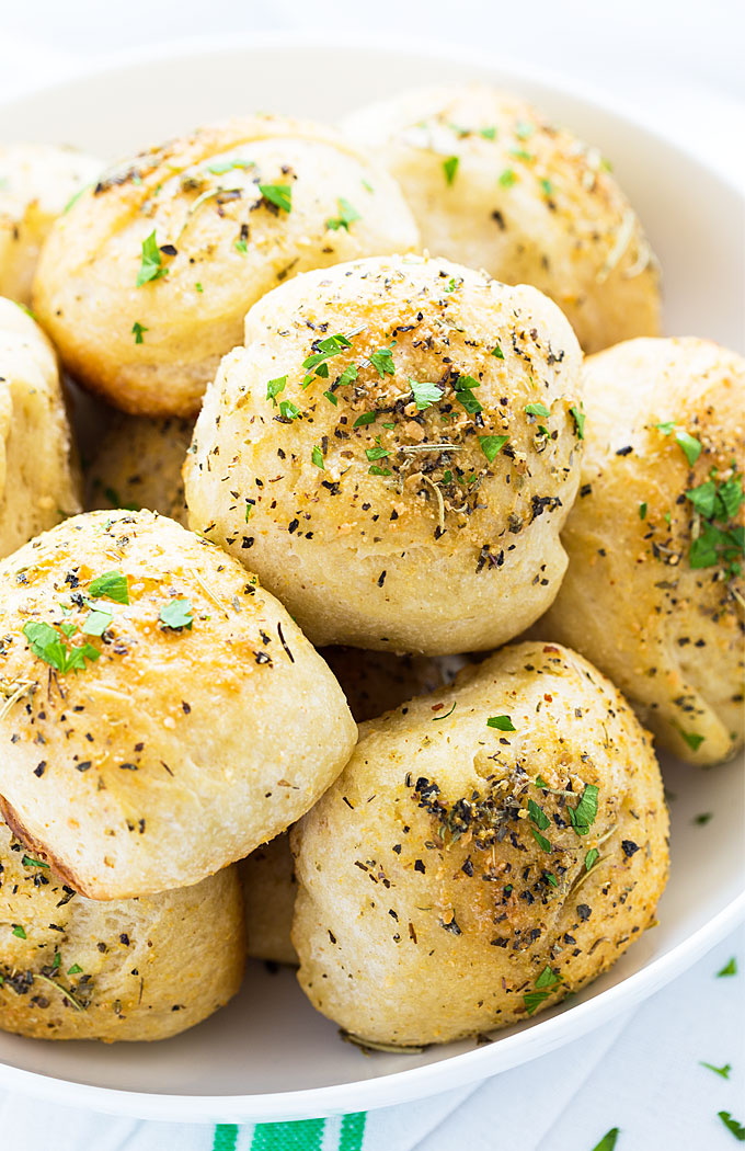 Closeup of herb dinner rolls in a white bowl.