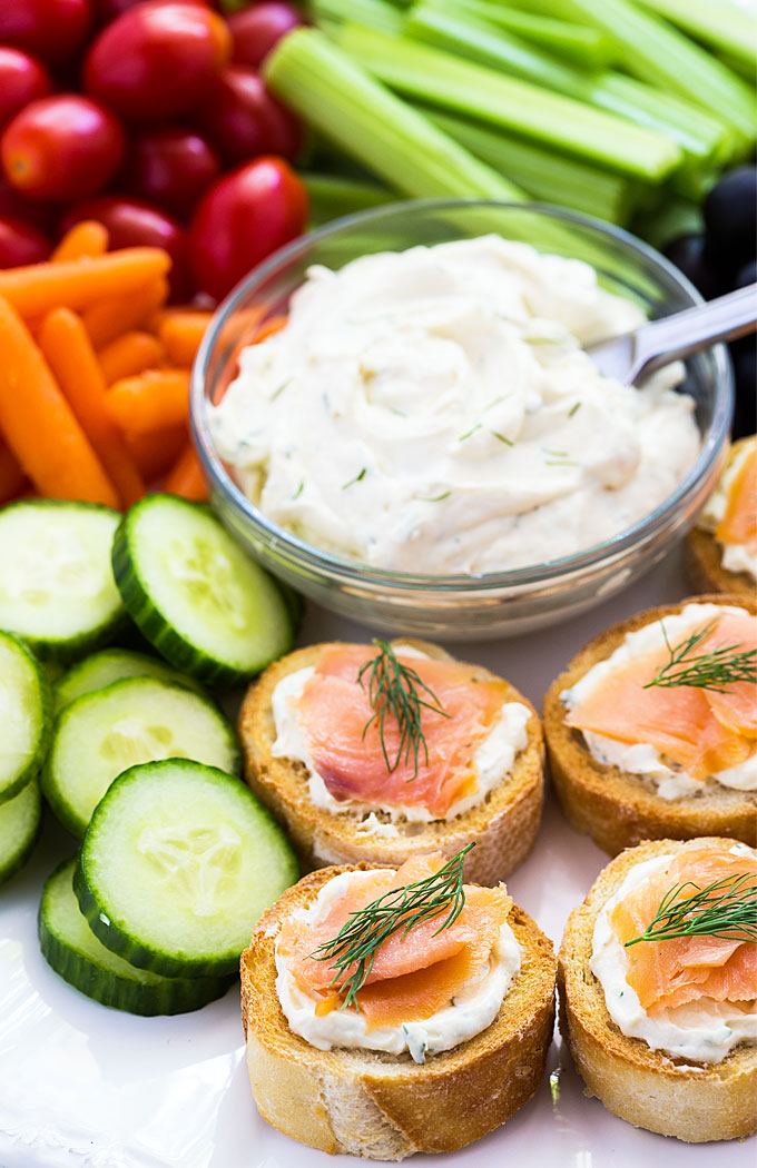 Smoked salmon appetizers on a platter with cream cheese spread and veggies.