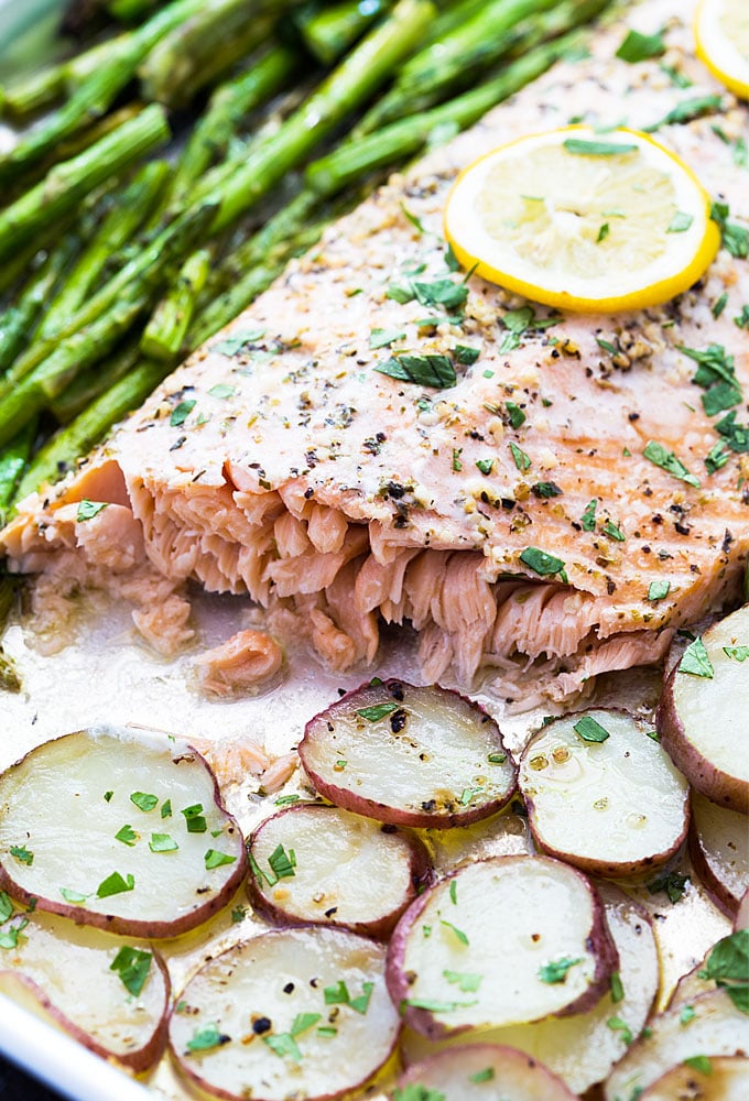 A closeup of baked salmon with potatoes and asparagus in a sheet pan.