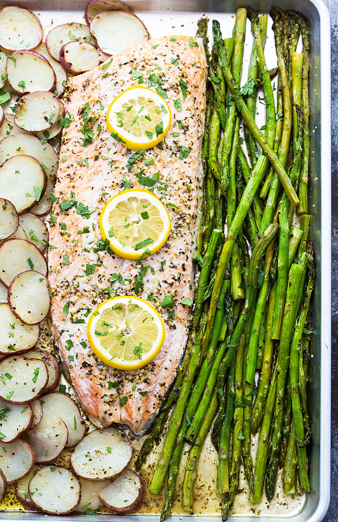 Overhead view of roasted salmon with potatoes and asparagus in a sheet pan.