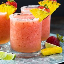 Front view of three frozen pineapple strawberry margaritas on a serving tray.