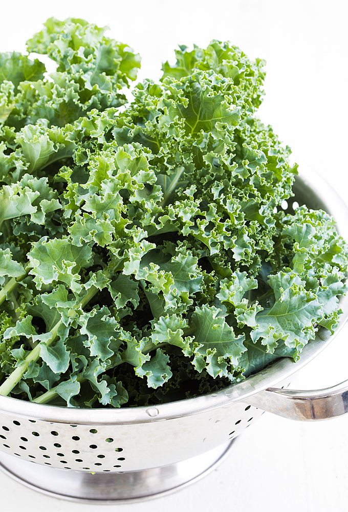 A closeup of fresh kale in a stainless colander.