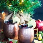 Two mule cocktails with pomegranates, lime and rosemary in copper mugs.