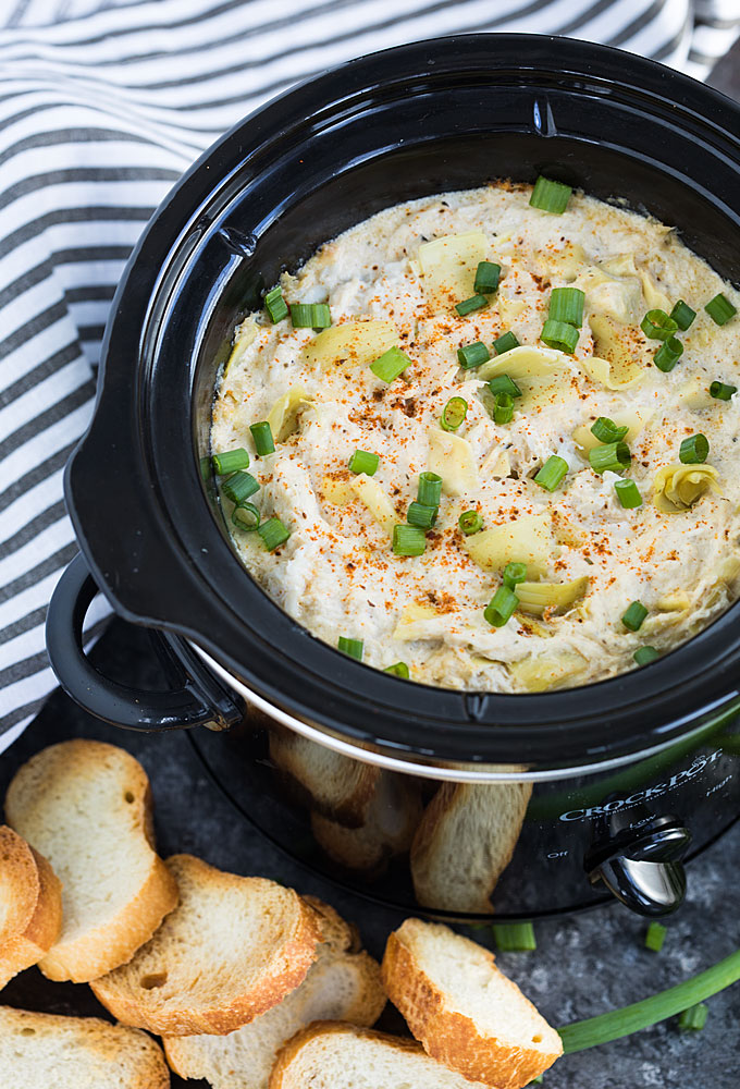 Crab dip with artichokes in a crock pot by toasted sliced French bread.