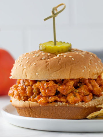 Front view of a turkey sloppy joe sandwich on a plate with potato chips.