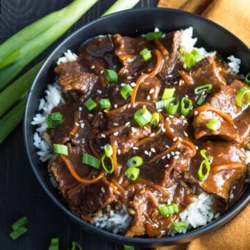 Mongolian beef over rice in a black bowl.