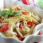 Chicken pasta salad in a square white bowl by a striped kitchen towel.