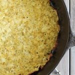 Overhead closeup view of a baked cauliflower crust in a cast iron skillet.